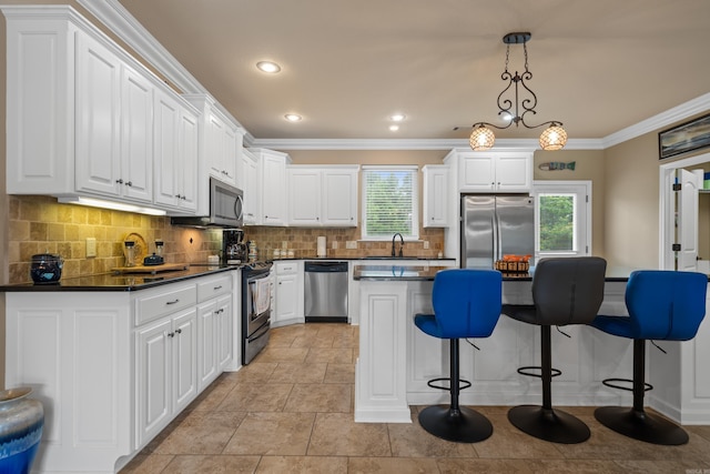 kitchen with decorative backsplash, crown molding, appliances with stainless steel finishes, dark countertops, and a kitchen breakfast bar