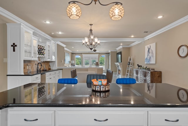 kitchen with stainless steel dishwasher, dark countertops, white cabinets, and ornamental molding