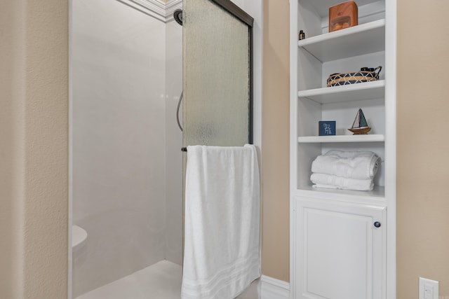 bathroom with a shower stall and built in shelves