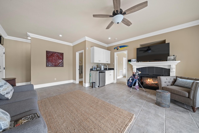 living area featuring crown molding, baseboards, a tiled fireplace, recessed lighting, and a ceiling fan