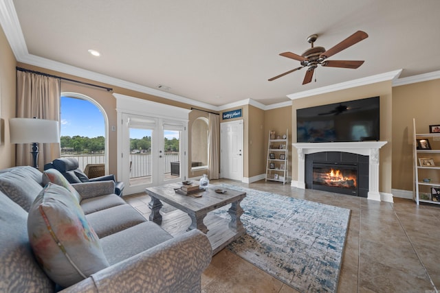 living area with tile patterned floors, ornamental molding, a fireplace, baseboards, and ceiling fan