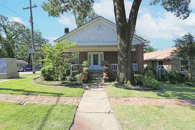 view of front of property with brick siding, covered porch, and a front yard