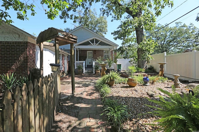 rear view of house with brick siding, covered porch, and fence