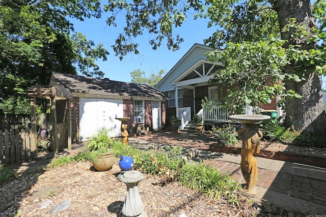 view of front of house featuring brick siding, covered porch, an outdoor structure, and fence