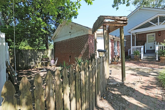 view of property exterior with brick siding and fence