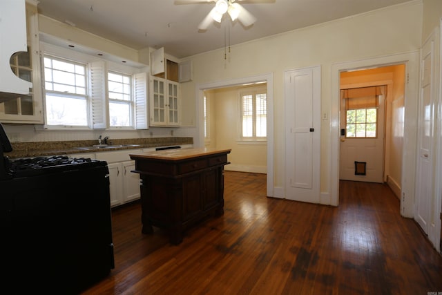 kitchen with black gas stove, dark wood-style floors, a ceiling fan, and a healthy amount of sunlight