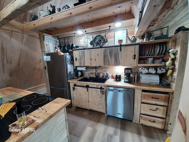 kitchen featuring wooden walls, dark wood finished floors, stainless steel appliances, wood counters, and a sink