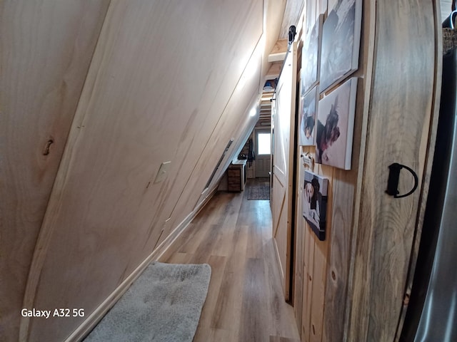 corridor with light wood-style floors and vaulted ceiling