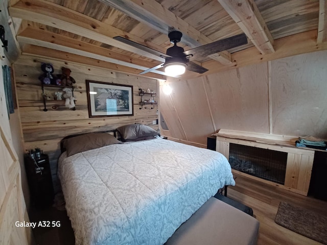 bedroom with beamed ceiling, a ceiling fan, wood finished floors, wooden walls, and wooden ceiling