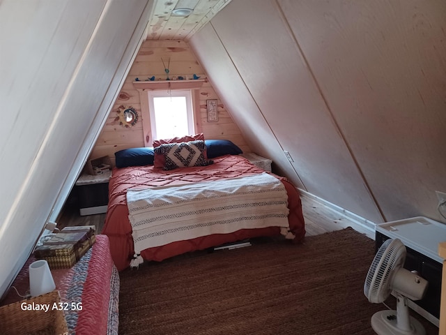 bedroom with wooden walls, lofted ceiling, and wood finished floors