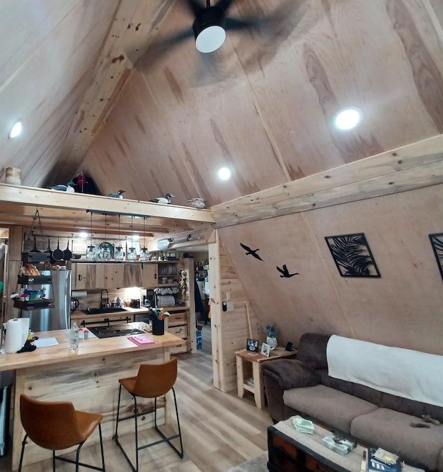 interior space with lofted ceiling, light wood-style flooring, freestanding refrigerator, butcher block countertops, and a sink