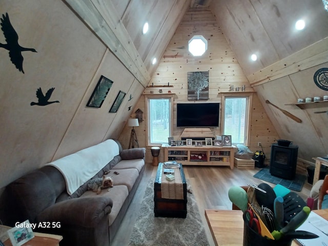 living room with high vaulted ceiling, a wood stove, and wood finished floors