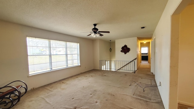 unfurnished room with carpet flooring, a textured ceiling, and a ceiling fan