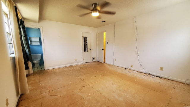 unfurnished room with a ceiling fan, visible vents, and baseboards