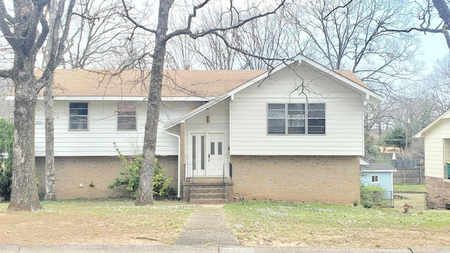 split foyer home with entry steps, brick siding, and roof with shingles