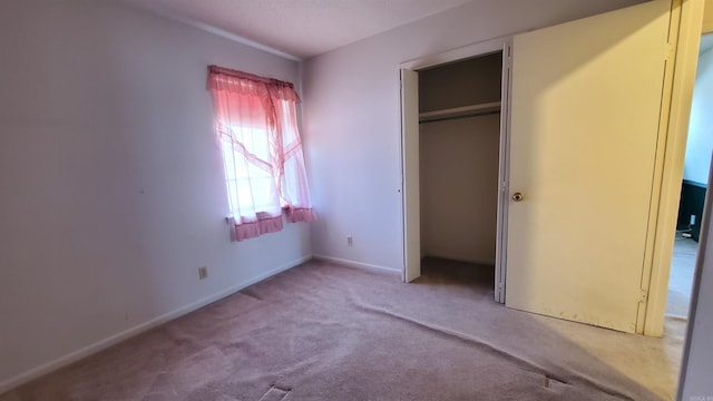 unfurnished bedroom featuring carpet, baseboards, and a closet