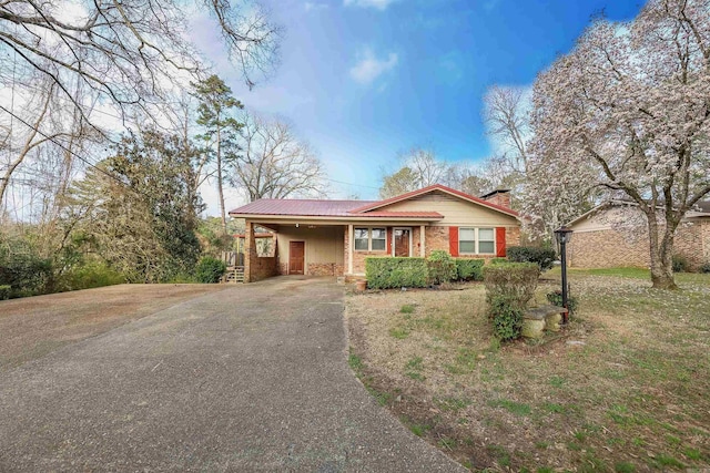 ranch-style house featuring an attached carport, brick siding, driveway, and a chimney