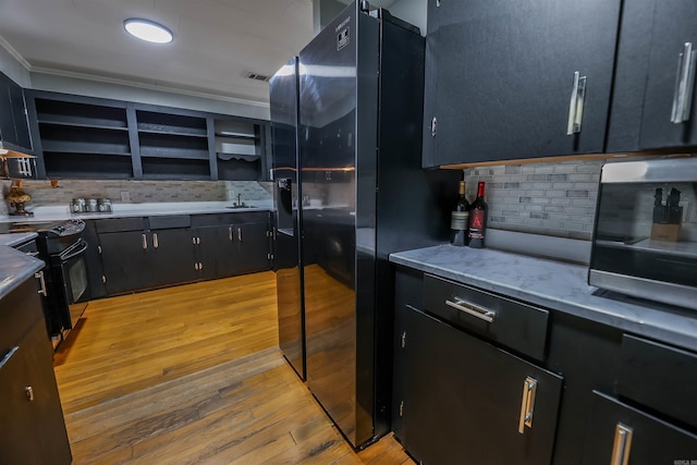 kitchen with black appliances, dark cabinets, backsplash, and light wood-type flooring
