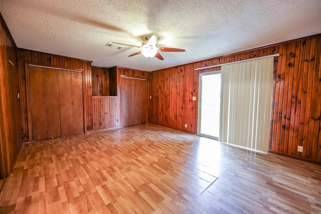 spare room featuring visible vents, a ceiling fan, light wood-type flooring, and a textured ceiling