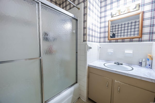 full bath with vanity, tile walls, shower / bath combination with glass door, and wallpapered walls