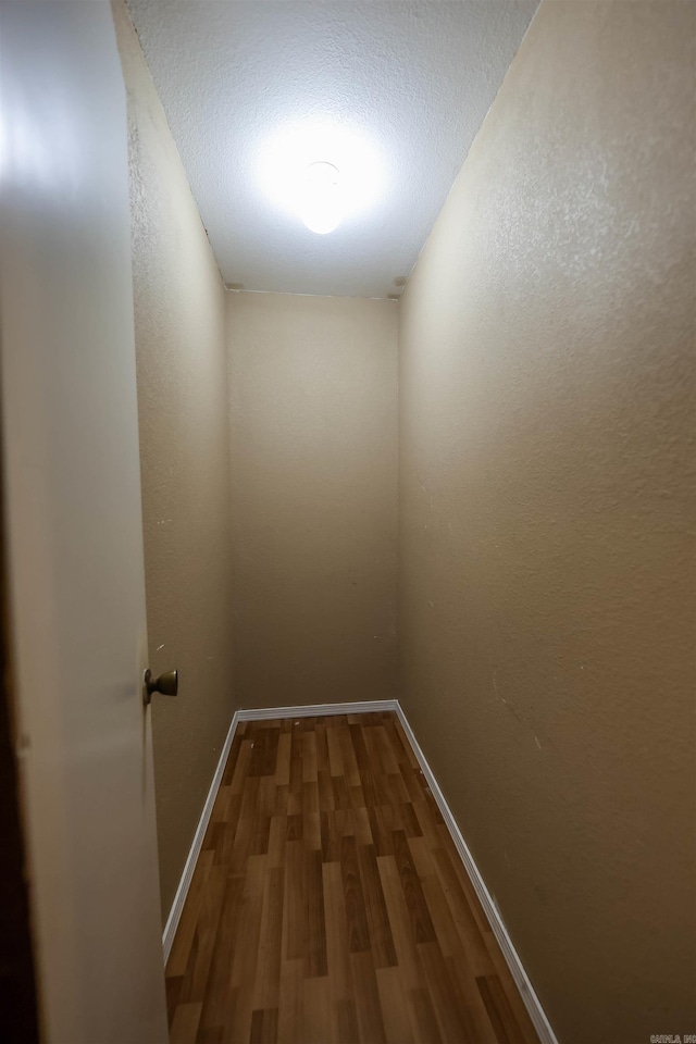 hallway featuring baseboards and wood finished floors