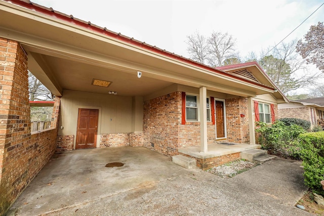doorway to property with an attached carport and brick siding