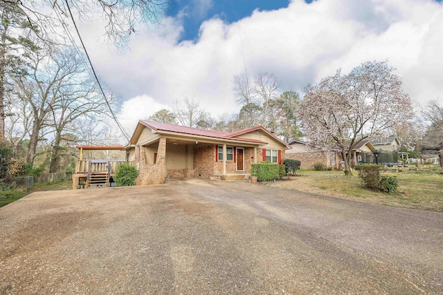 ranch-style house featuring an attached carport, fence, driveway, a wooden deck, and metal roof