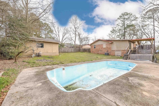 view of swimming pool with fence, stairway, a lawn, a deck, and an empty pool