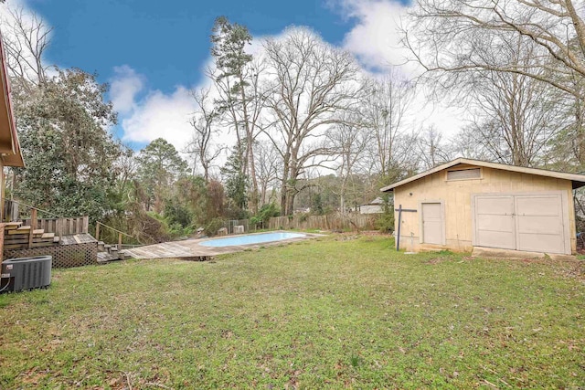 view of yard with a fenced in pool, a detached garage, fence, cooling unit, and an outdoor structure