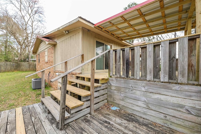 deck with cooling unit, a lawn, and fence