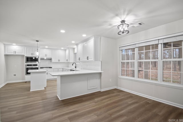 kitchen featuring visible vents, a sink, appliances with stainless steel finishes, white cabinets, and dark wood-style flooring