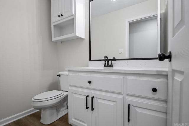 bathroom featuring vanity, toilet, wood finished floors, and baseboards