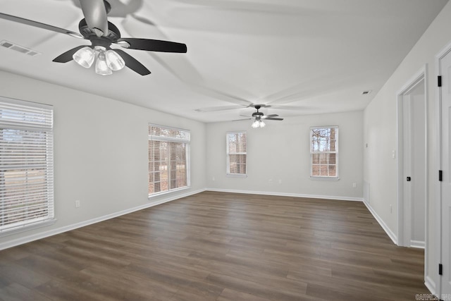 empty room with dark wood-style floors, visible vents, baseboards, and ceiling fan