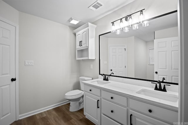 bathroom with visible vents, toilet, wood finished floors, and a sink