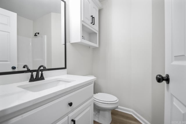 full bathroom with toilet, wood finished floors, a shower, baseboards, and vanity