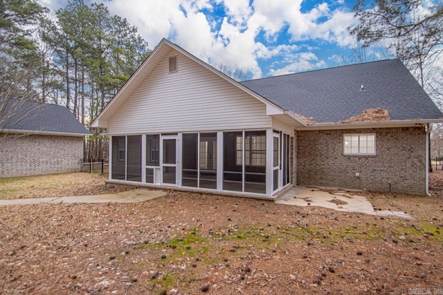 back of property with brick siding, a shingled roof, and a sunroom