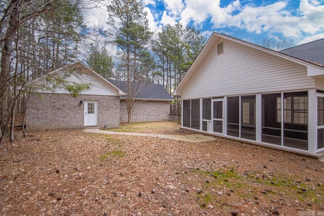 back of house featuring brick siding and a sunroom