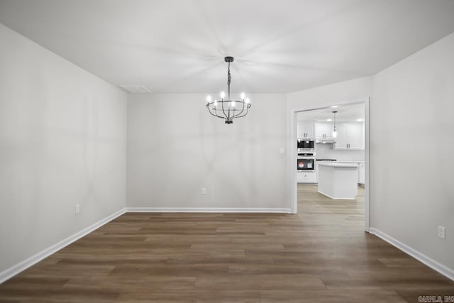 unfurnished dining area featuring baseboards, wood finished floors, and a chandelier