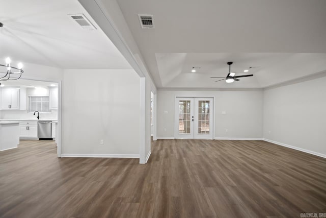 unfurnished living room with a tray ceiling, visible vents, baseboards, and dark wood-style flooring