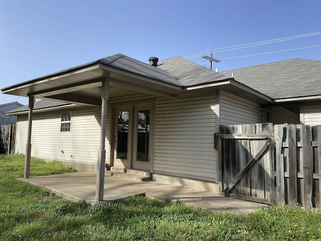 rear view of property with a patio area, a shingled roof, a yard, and fence