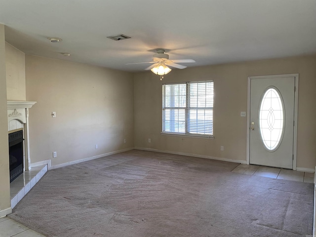 entrance foyer with visible vents, baseboards, ceiling fan, light carpet, and a tile fireplace