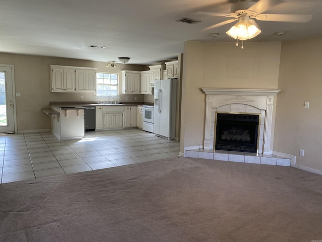 kitchen featuring a sink, white appliances, visible vents, and light carpet