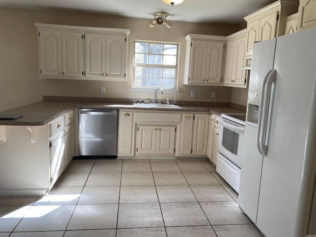 kitchen featuring a sink, dark countertops, white appliances, a peninsula, and light tile patterned flooring