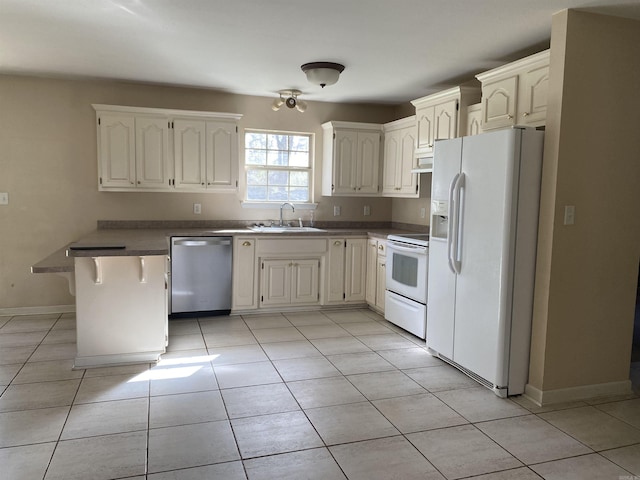 kitchen featuring white appliances, a breakfast bar area, baseboards, light tile patterned flooring, and a sink