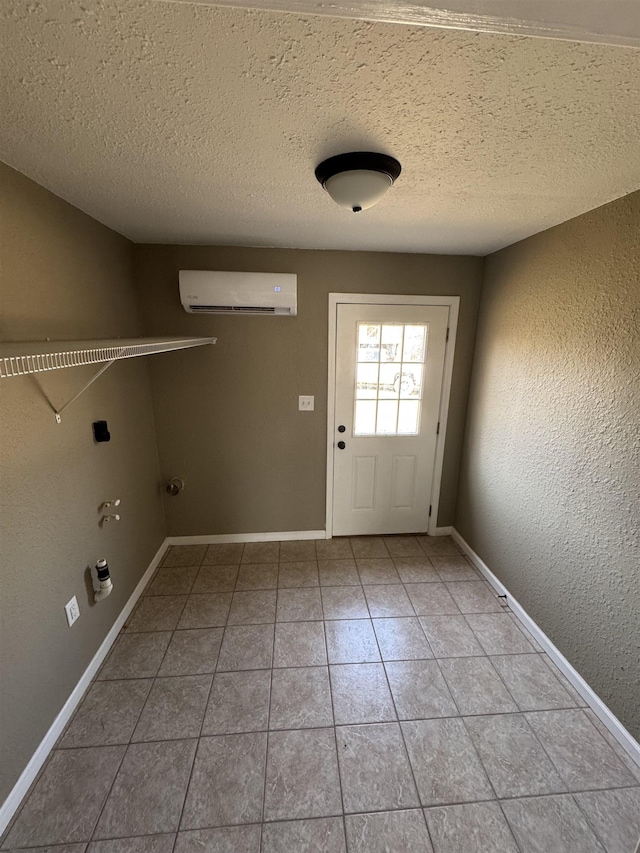 laundry area with a textured wall, baseboards, laundry area, and a wall mounted AC