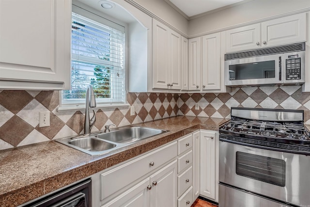 kitchen featuring a sink, appliances with stainless steel finishes, white cabinetry, and tile counters