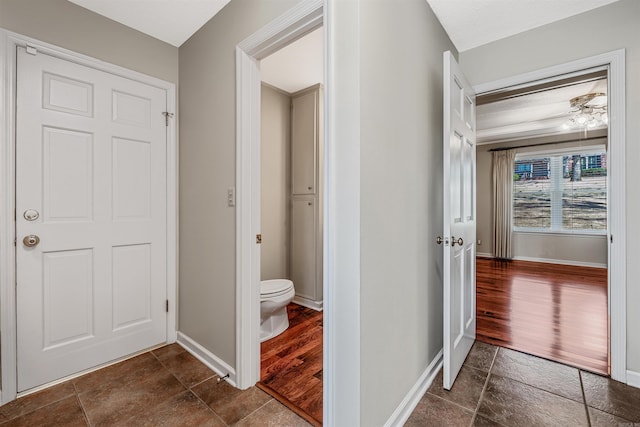 bathroom with stone tile floors, toilet, and baseboards