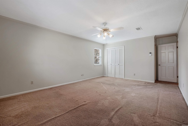 unfurnished bedroom with visible vents, light carpet, a closet, crown molding, and baseboards