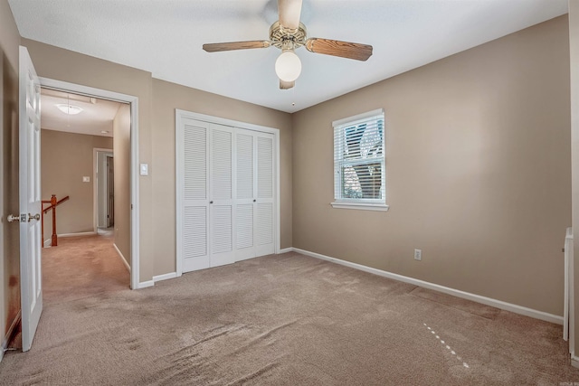 unfurnished bedroom with a closet, carpet flooring, a ceiling fan, and baseboards