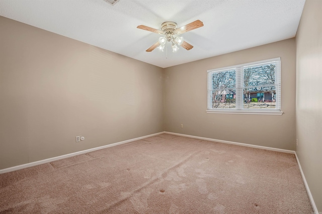 spare room featuring a ceiling fan, carpet, and baseboards